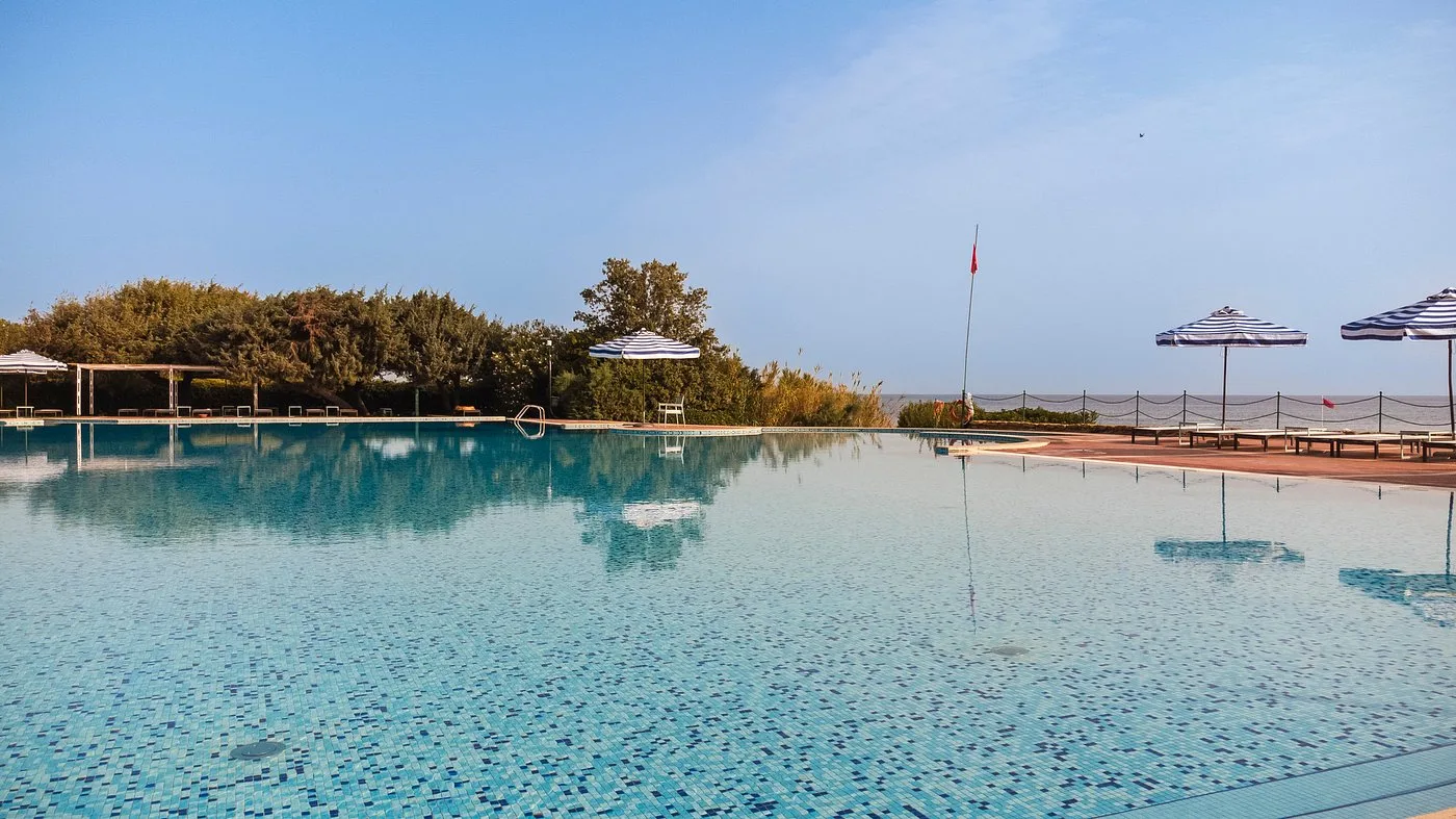 Piscina panoramica vista mare con ombrelloni e vegetazione mediterranea