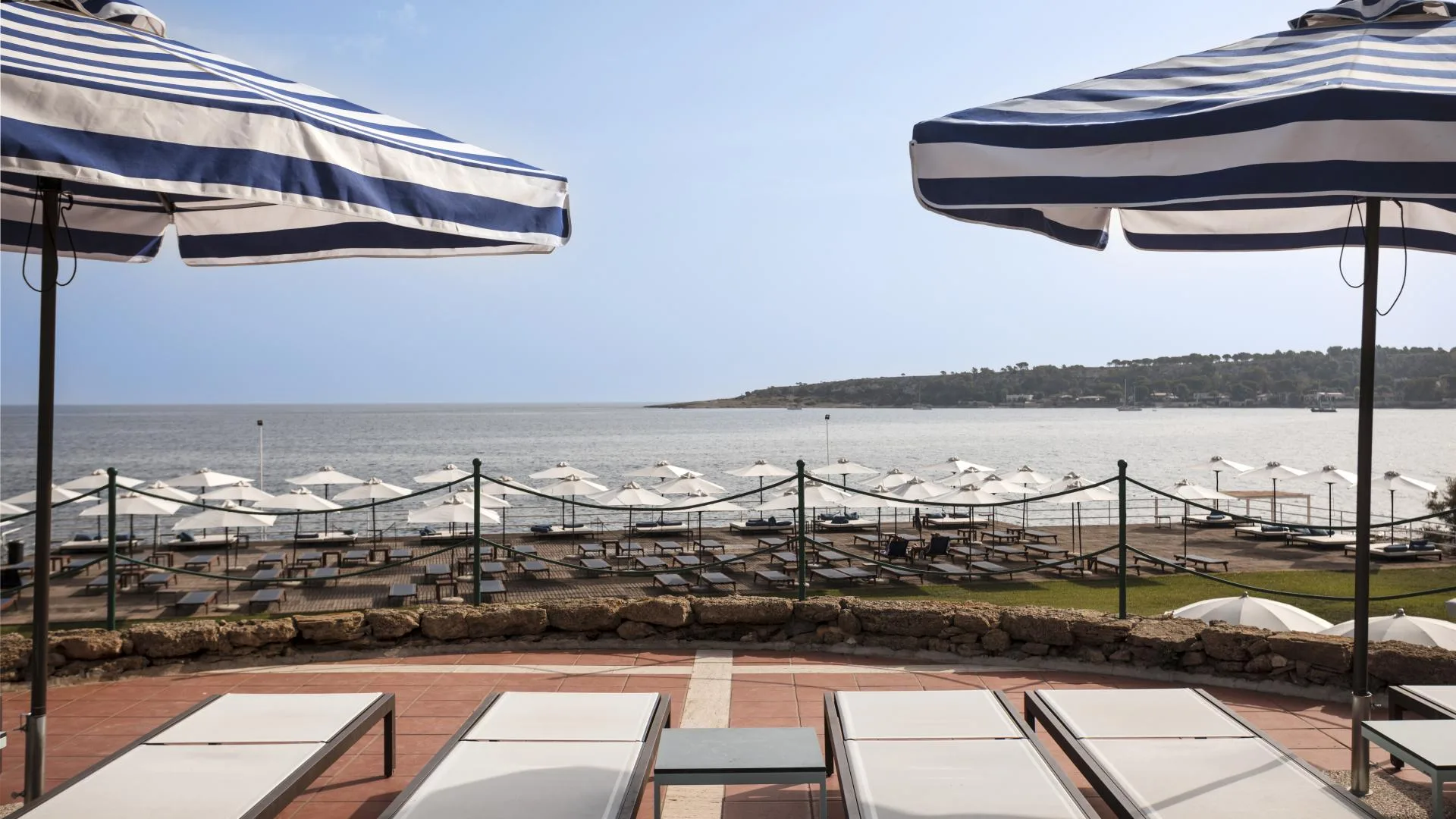 Terrazza con lettini e ombrelloni a righe vista mare