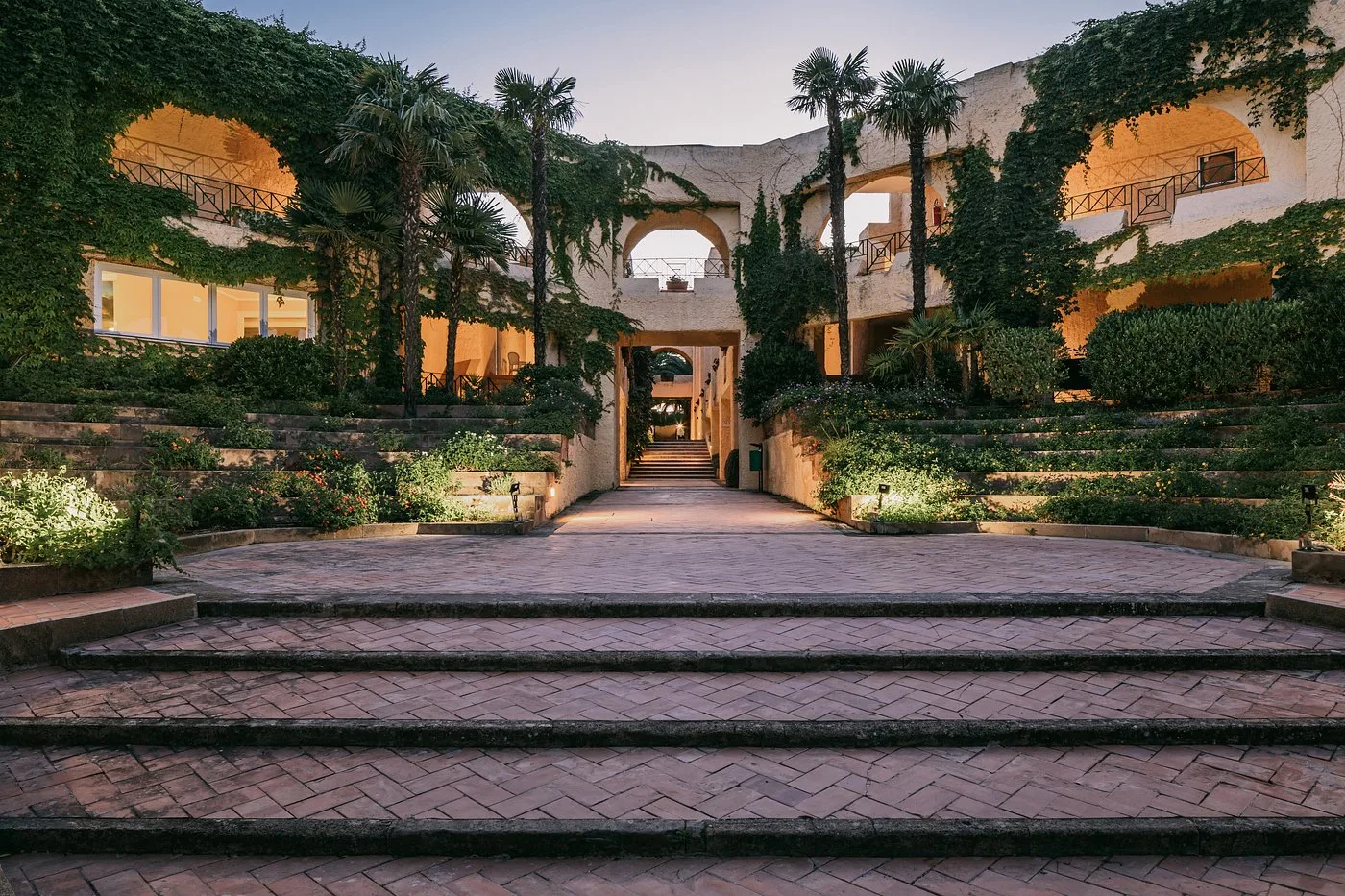 Ingresso del resort al tramonto con archi ricoperti di edera e scalinate