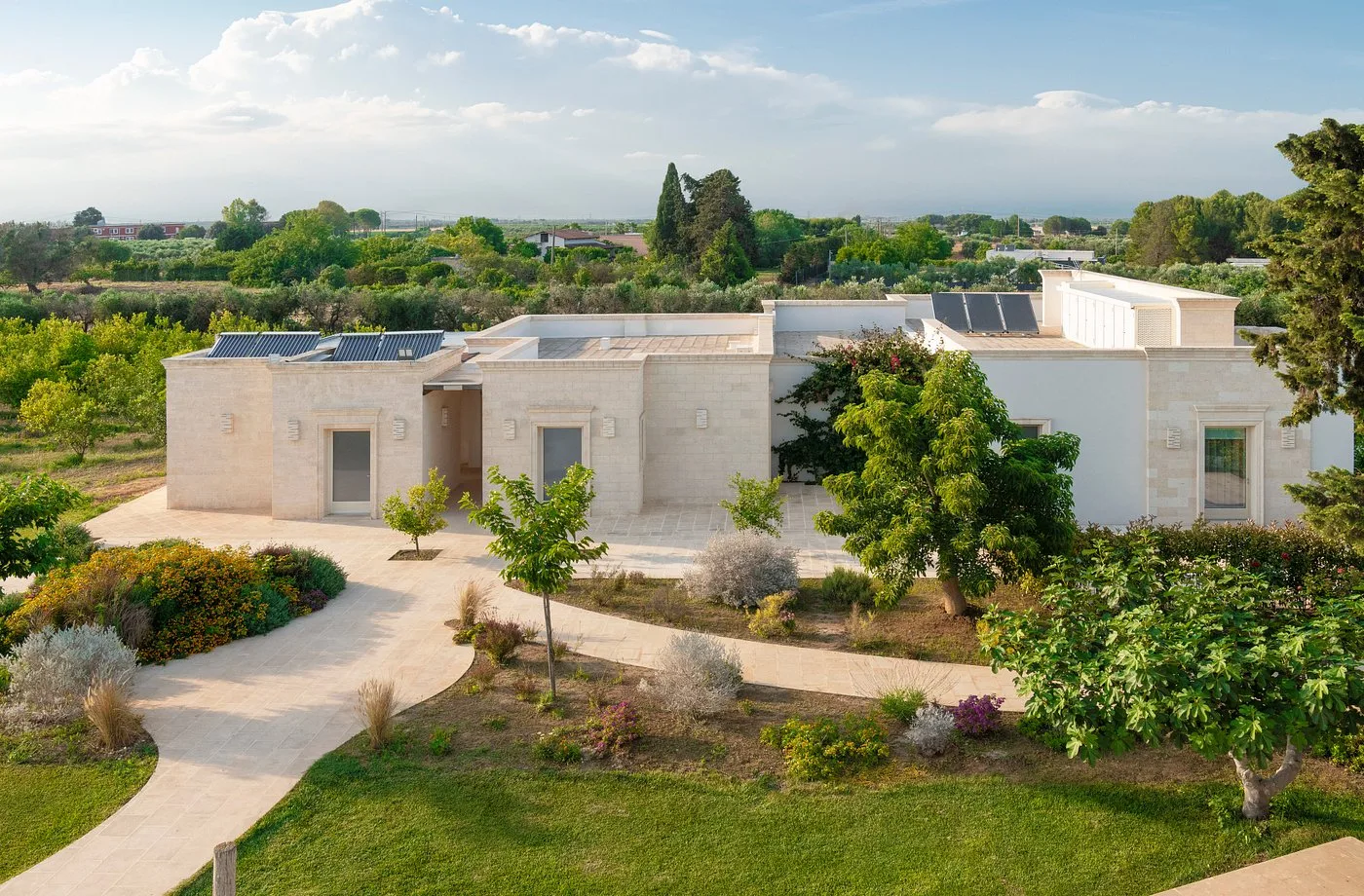Veduta aerea della masseria in pietra chiara circondata da giardino e uliveti
