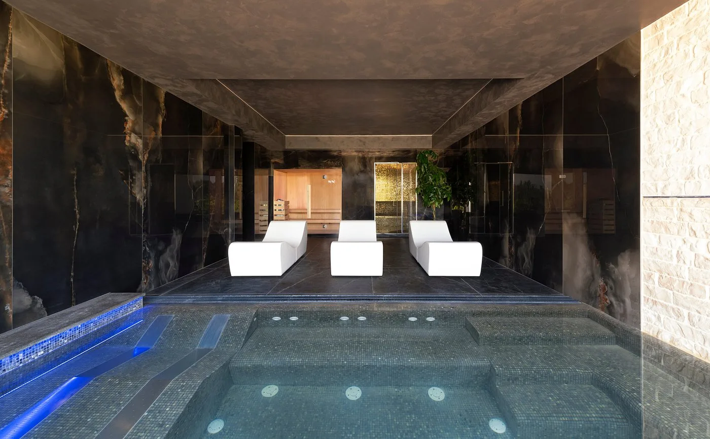 Area benessere della spa con vasca idromassaggio e lettini bianchi