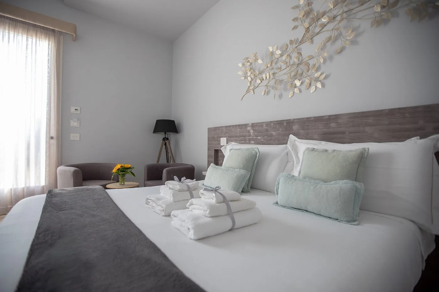 Camera luminosa con letto matrimoniale, poltrone e decorazione floreale dorata