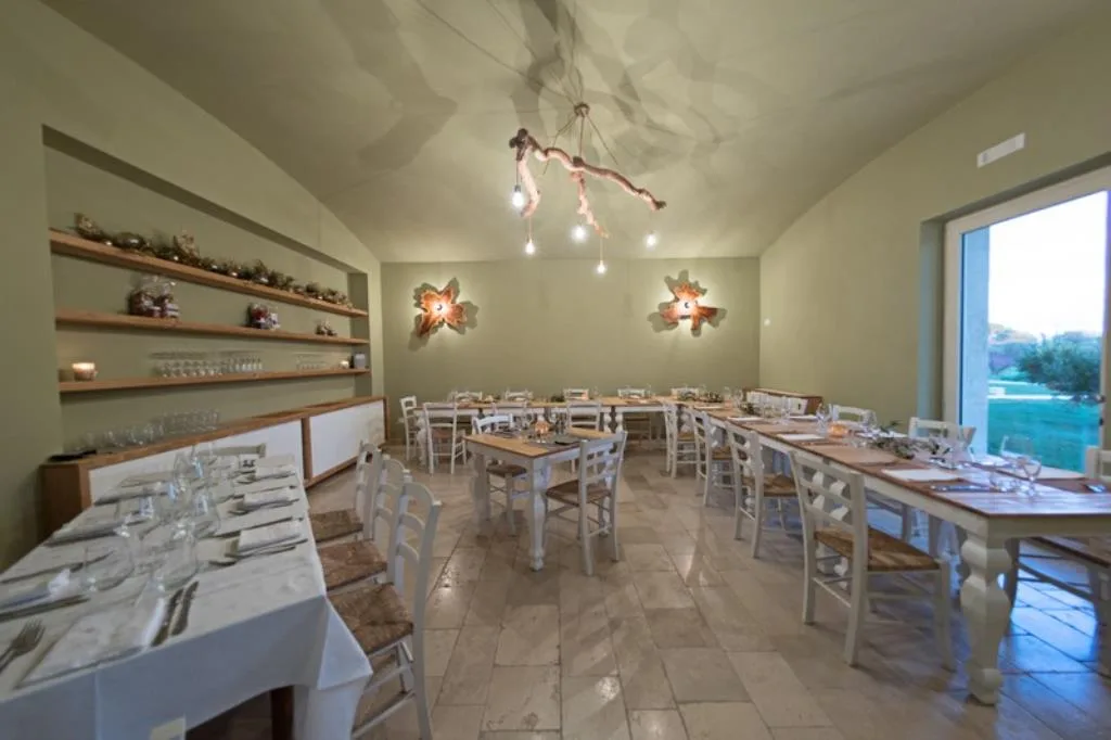 Sala ristorante interna con tavoli apparecchiati e lampadario in legno naturale
