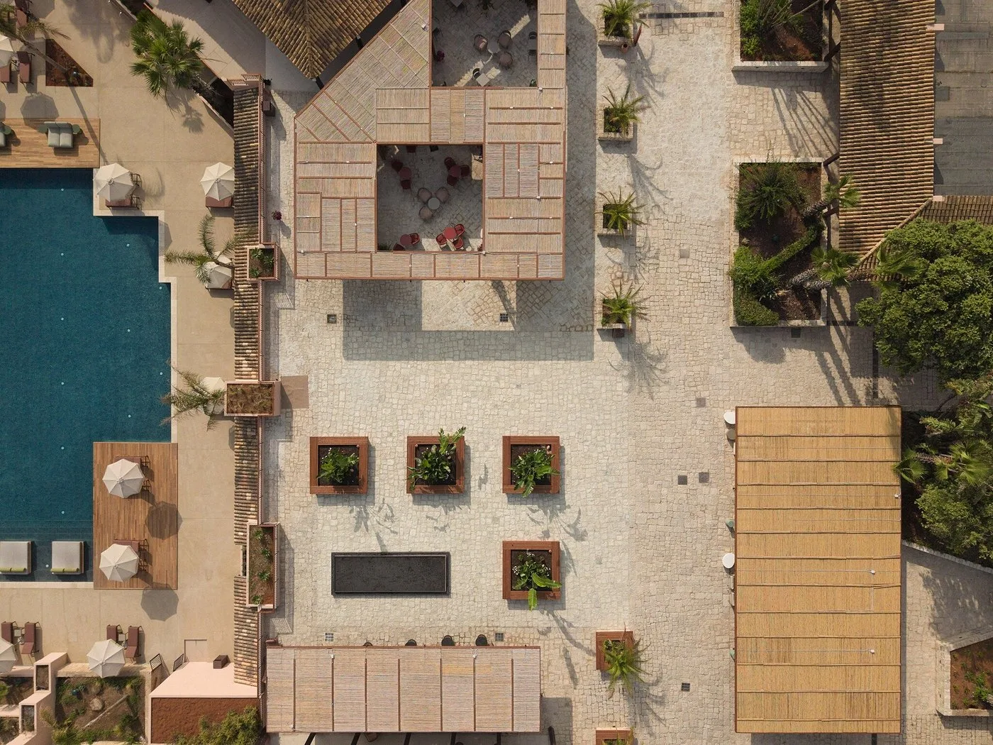 Vista aerea dall'alto del cortile del resort con pavimentazione in pietra e aree verdi
