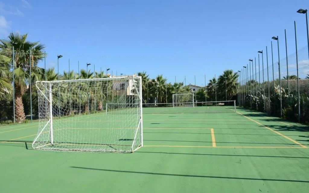 Campo sportivo polivalente all'aperto con porte da calcio e palme circostanti