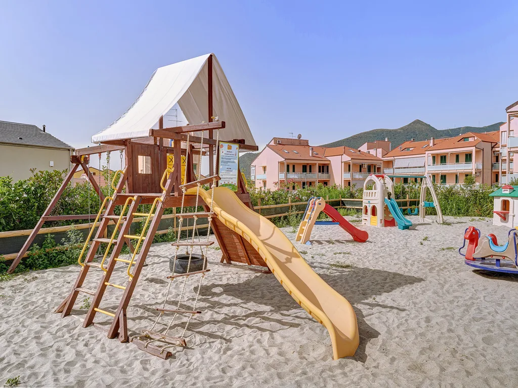 Parco giochi all'aperto con scivoli e altalene su sabbia