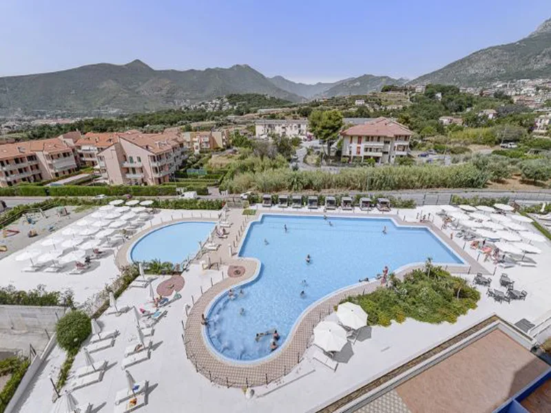 Vista panoramica della piscina del resort tra colline e abitazioni
