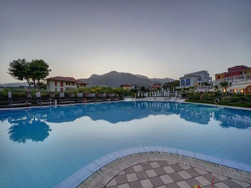 Piscina all'aperto al tramonto con riflessi delle montagne