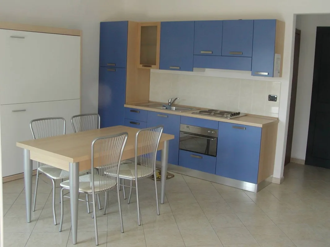 Cucina blu con forno e lavello e tavolo da pranzo in legno con sedie