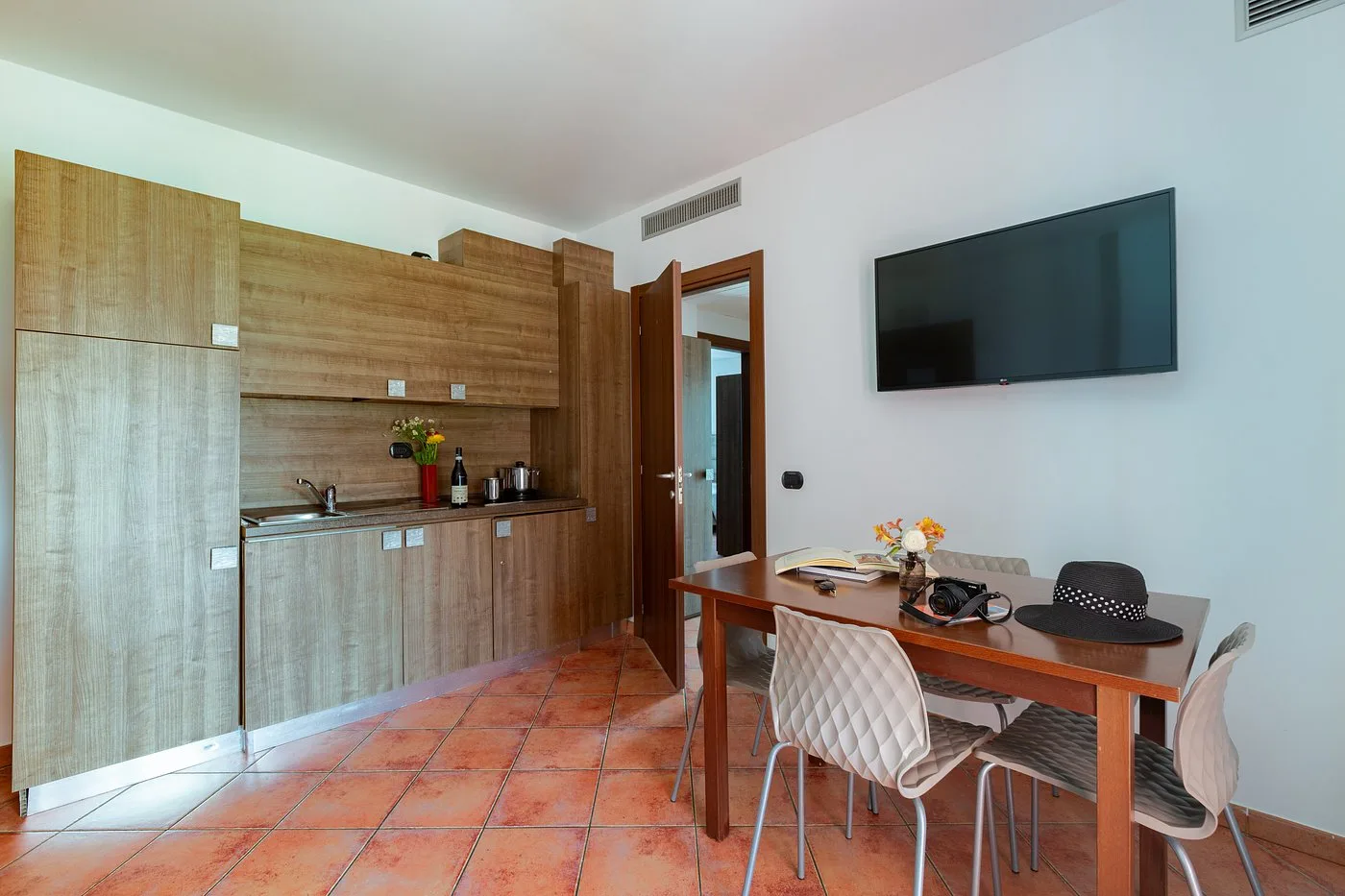 Appartamento con angolo cottura, tavolo da pranzo e TV a parete
