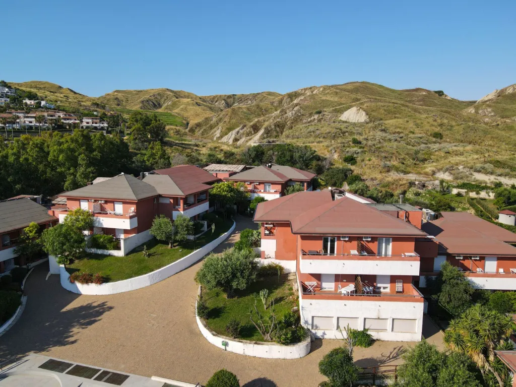Veduta aerea degli edifici residenziali del villaggio con tetti rossi immersi nel verde tra le colline