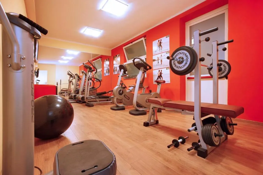 Palestra attrezzata con macchine cardio, pesi e pareti rosse