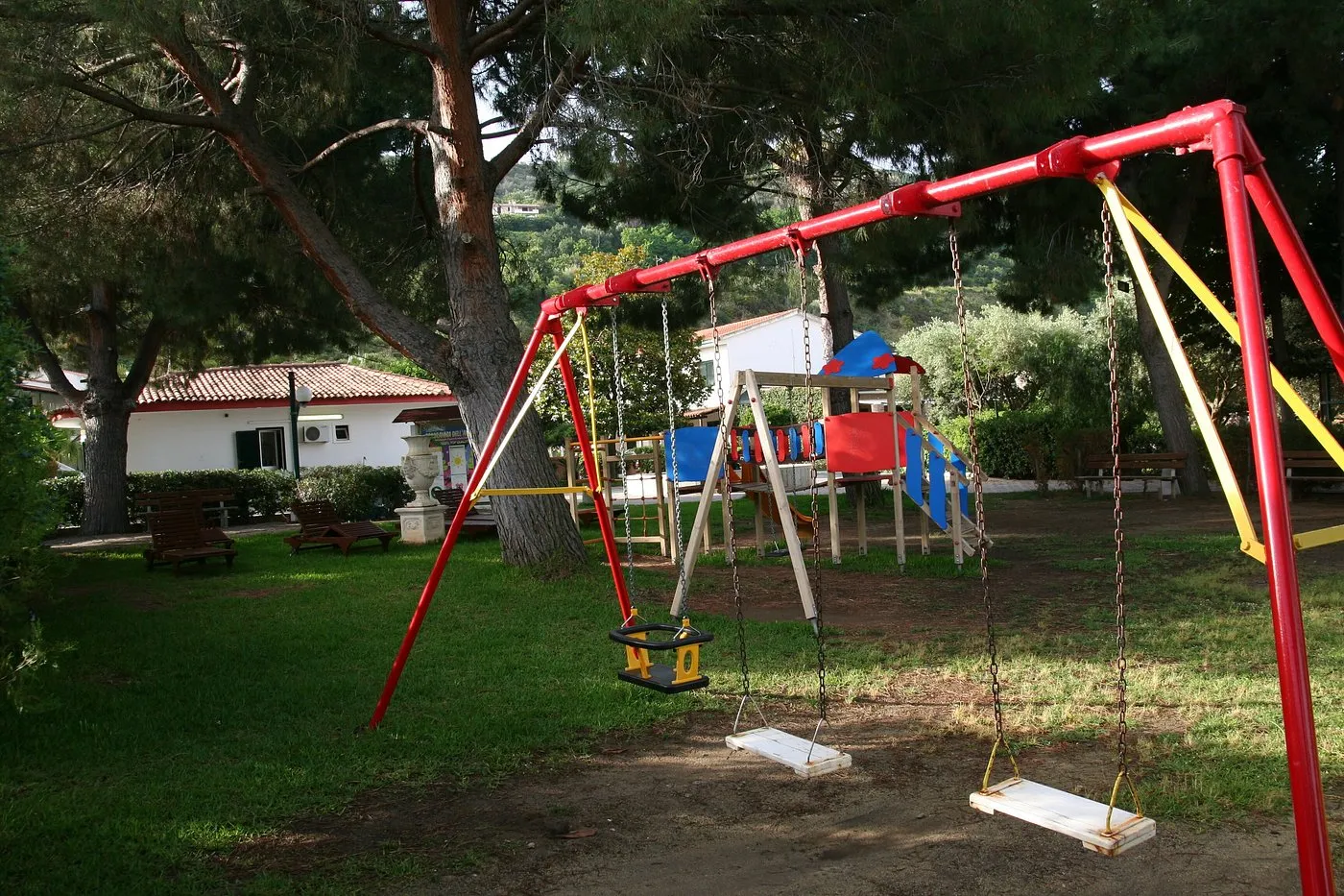 Parco giochi per bambini con altalene colorate e scivolo tra gli alberi