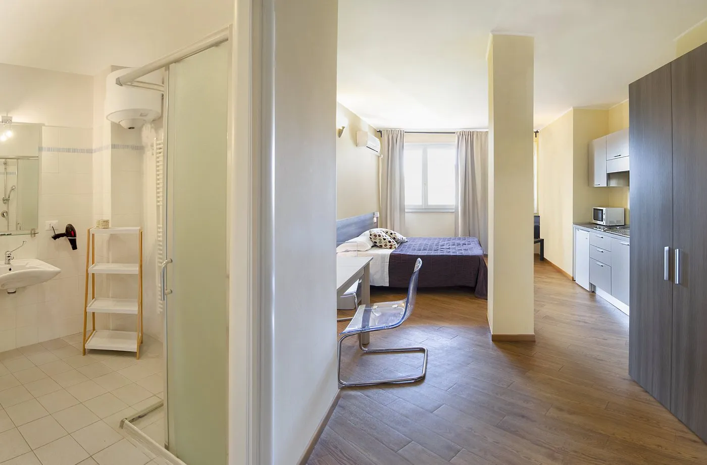 Monolocale con bagno con doccia, zona letto, scrivania e angolo cottura attrezzato