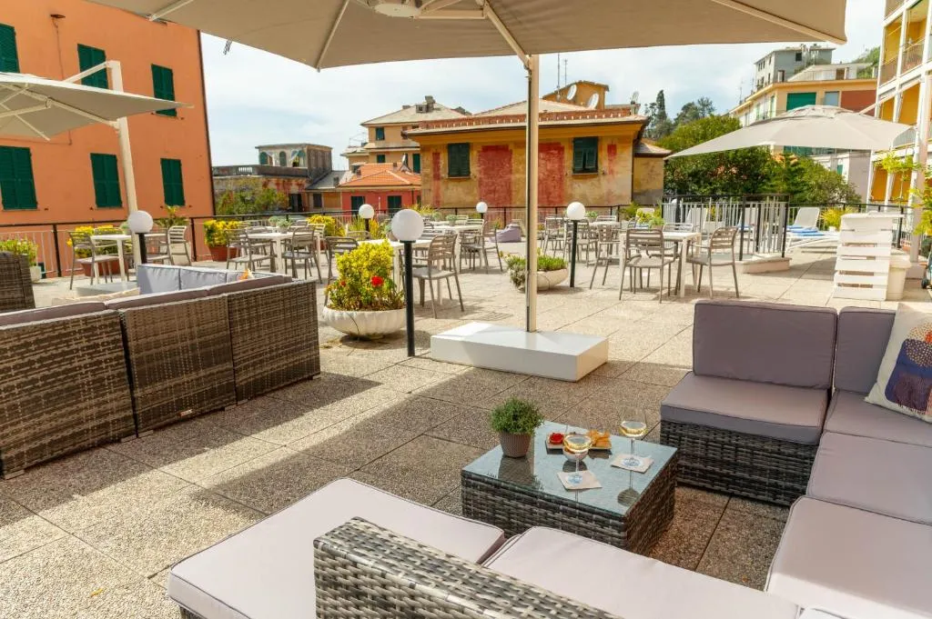 Ampia terrazza con tavoli, sedie e divani lounge tra palazzi colorati