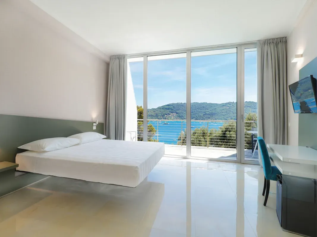 Camera moderna minimalista con letto sospeso e grande vetrata vista mare