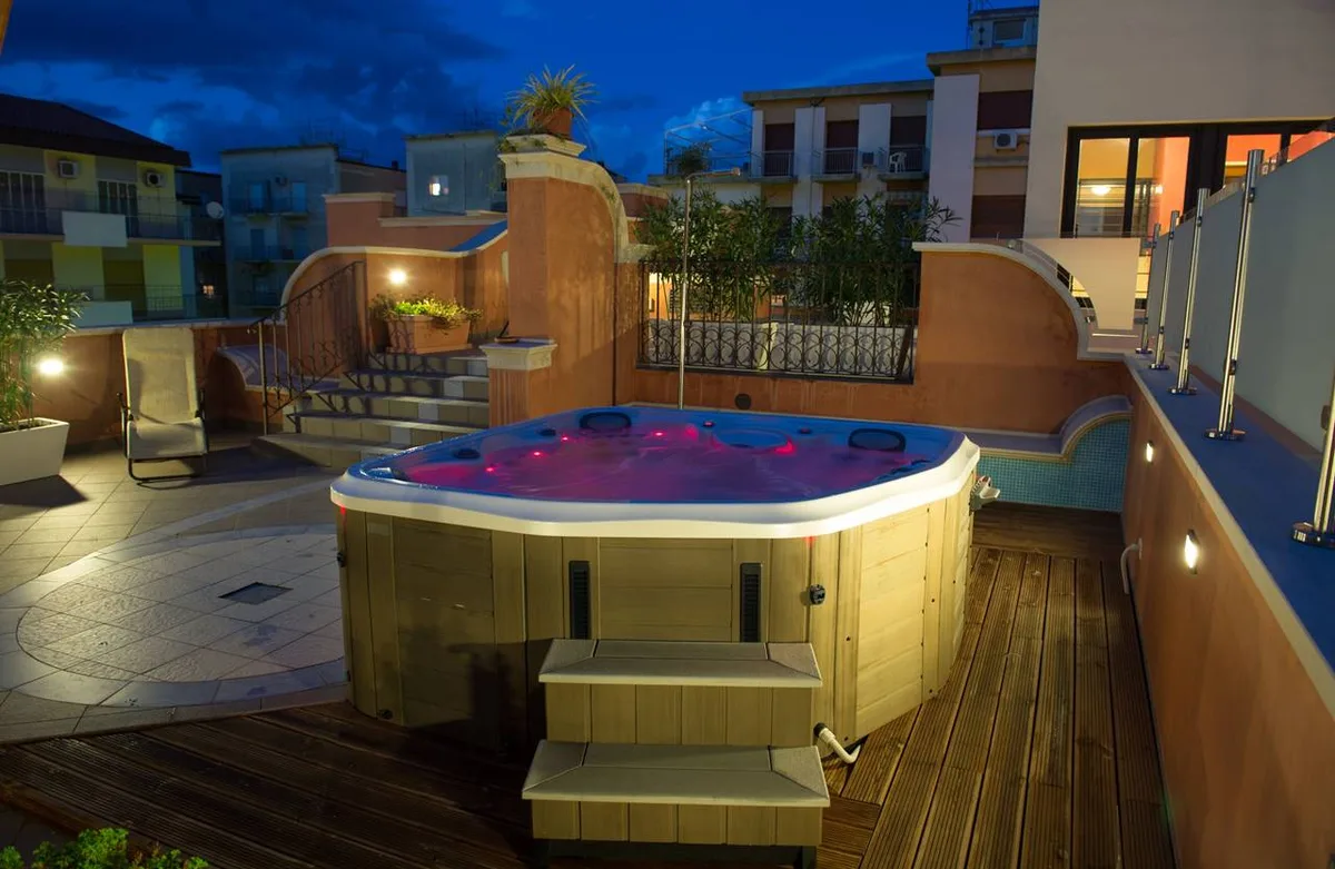 Vasca idromassaggio in legno illuminata di viola su terrazza al crepuscolo