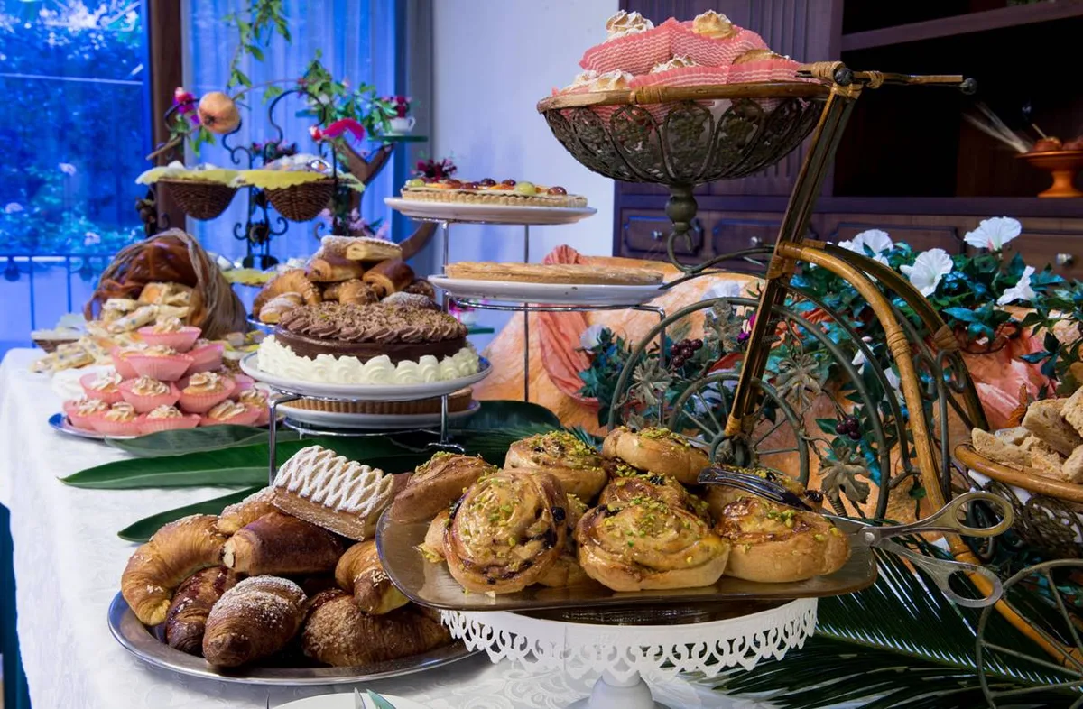 Buffet di dolci e pasticceria con torte, cornetti e brioche su alzate decorative