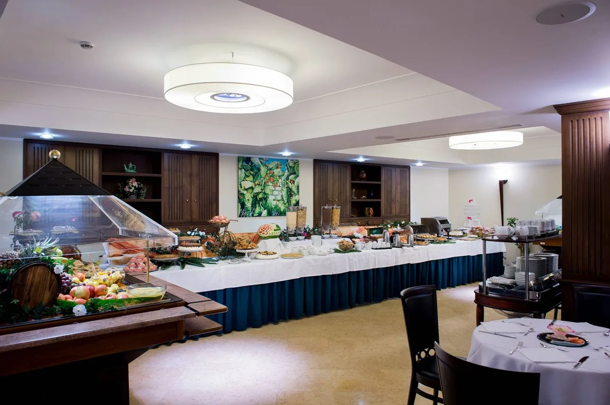 Sala buffet della colazione con banco espositivo di frutta, dolci e cereali