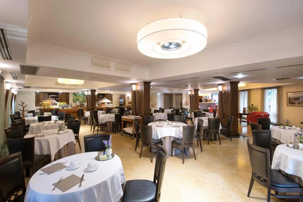 Ampia sala ristorante con tavoli apparecchiati, colonne in legno e illuminazione moderna