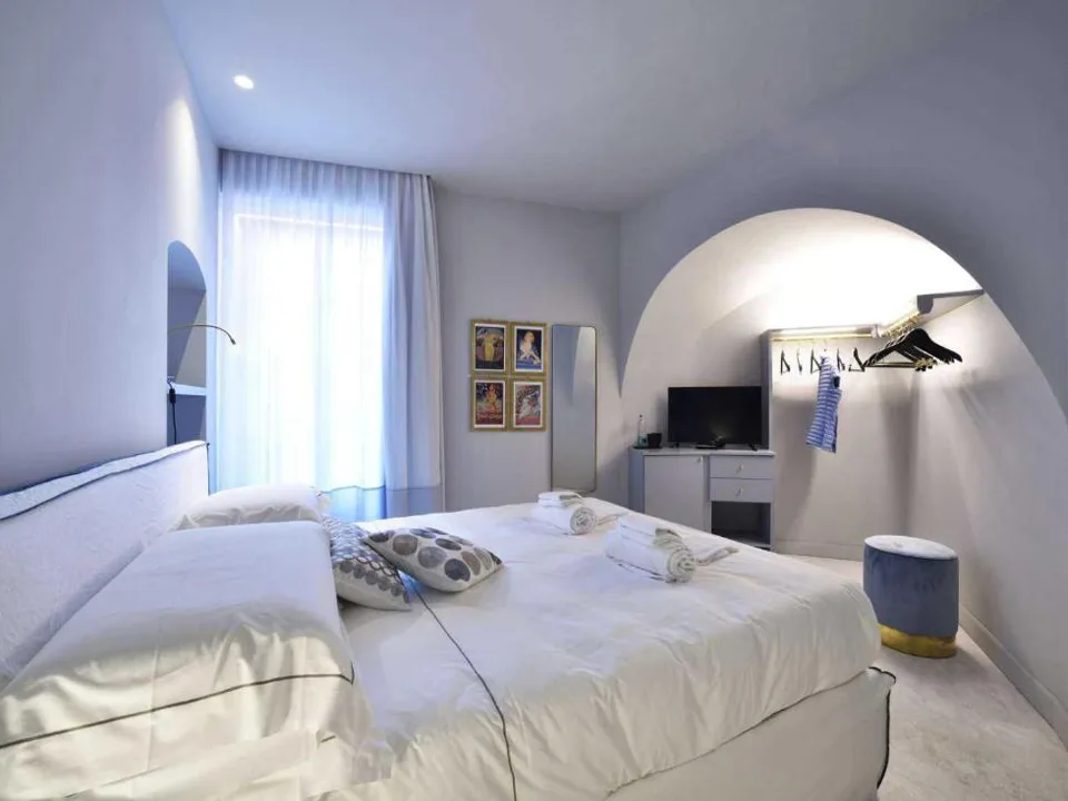 Camera da letto bianca con soffitto a volta, scrivania e area guardaroba