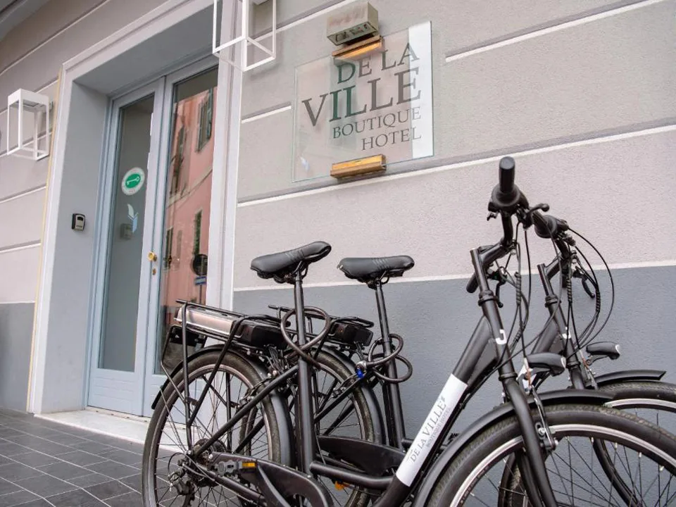 Insegna in vetro del De La Ville Boutique Hotel con biciclette parcheggiate all'ingresso