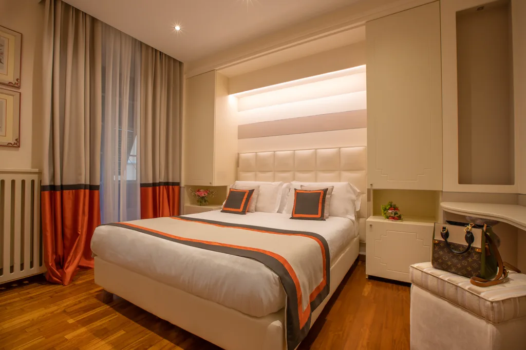 Camera moderna con letto matrimoniale, dettagli arancioni, tende coordinate e pavimento in parquet