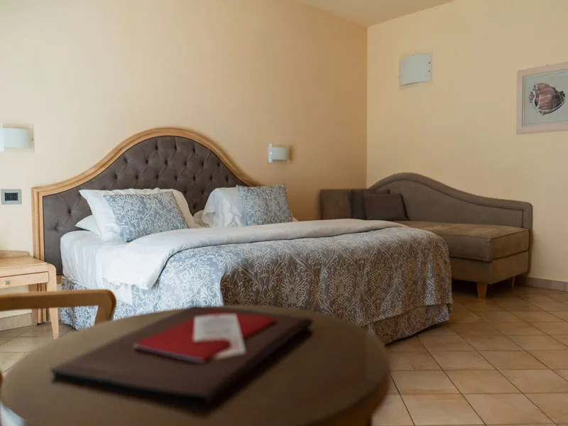 Camera matrimoniale con testiera grigia, divano e tavolino