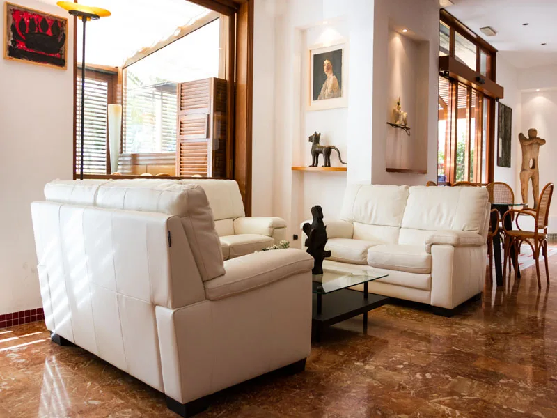 Hall dell'hotel con divani in pelle bianca, tavolino in vetro e sculture decorative