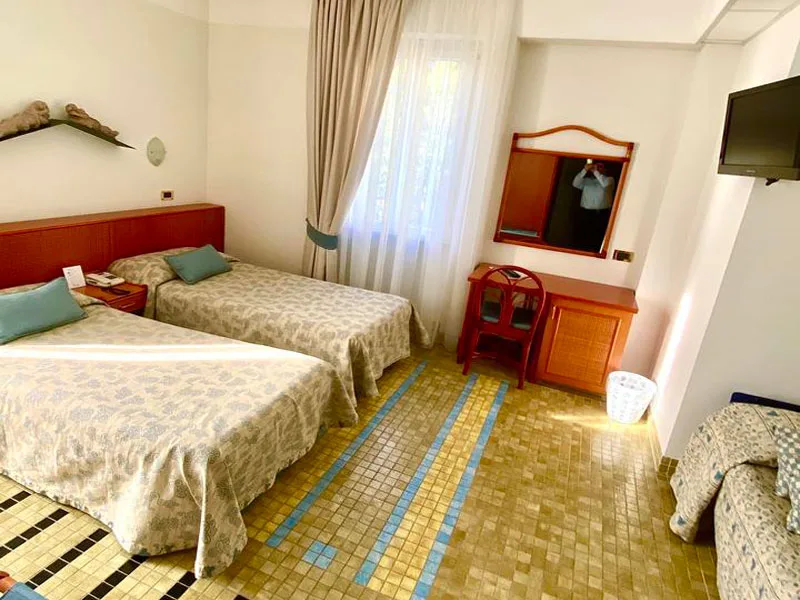 Camera tripla con due letti, copriletto a fantasia e pavimento a mosaico dorato