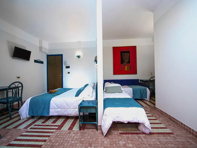 Ampia camera familiare con più letti, parete rossa decorativa e pavimento a mosaico colorato