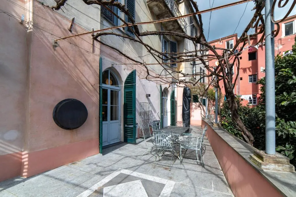 Terrazza esterna con pergolato, tavolo e sedie in ferro battuto tra edifici colorati