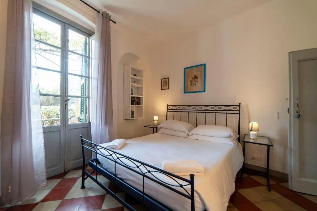 Camera da letto con letto in ferro battuto, porta-finestra e pavimento a scacchi
