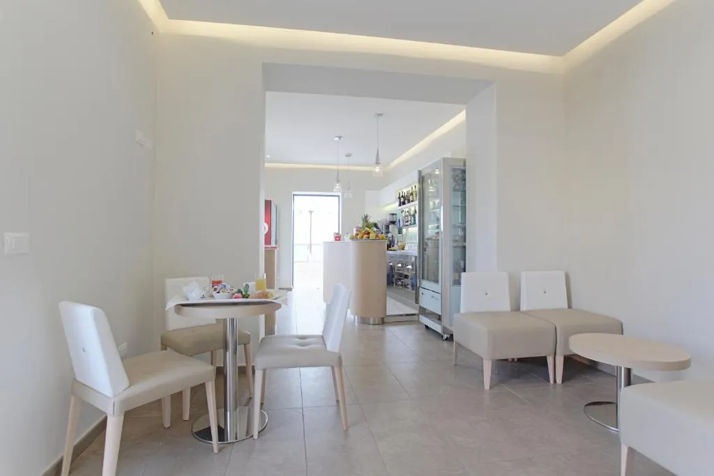 Area bar e soggiorno con sedute bianche, tavolini e arredo moderno