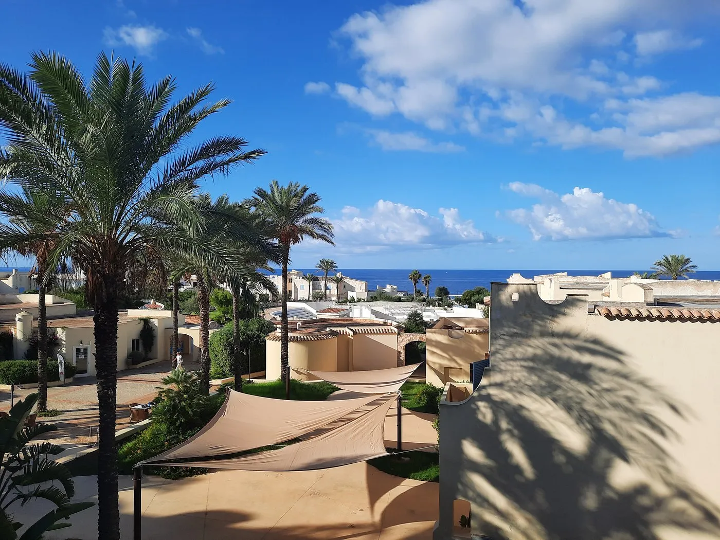 Vista panoramica del resort con palme e tende ombreggianti verso il mare