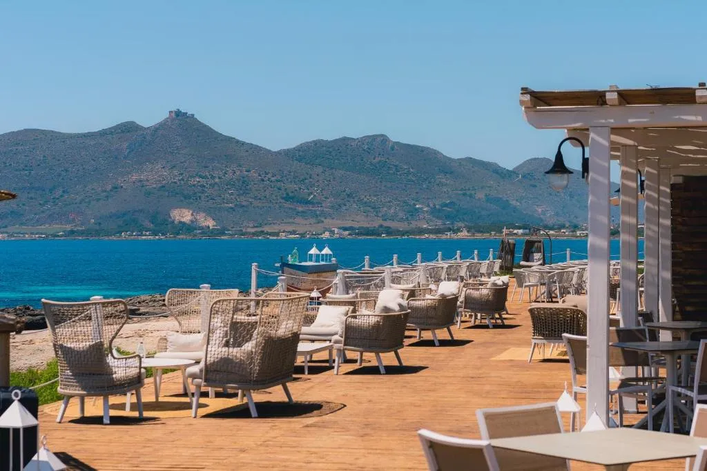 Terrazza ristorante in legno con poltrone in vimini e vista mare e montagne