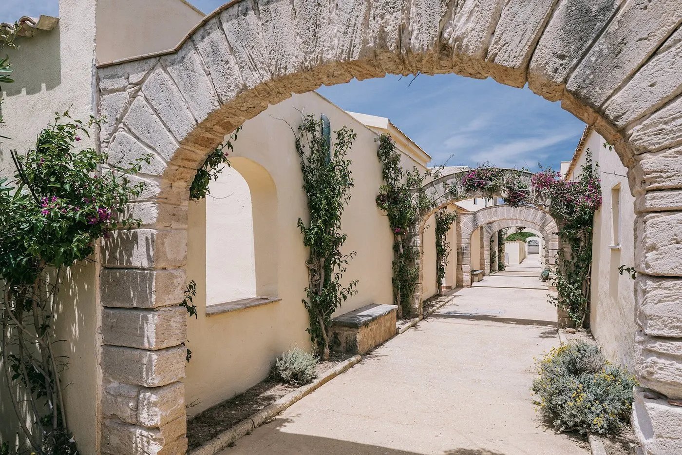 Vialetto con archi in pietra e piante di bouganville fiorite