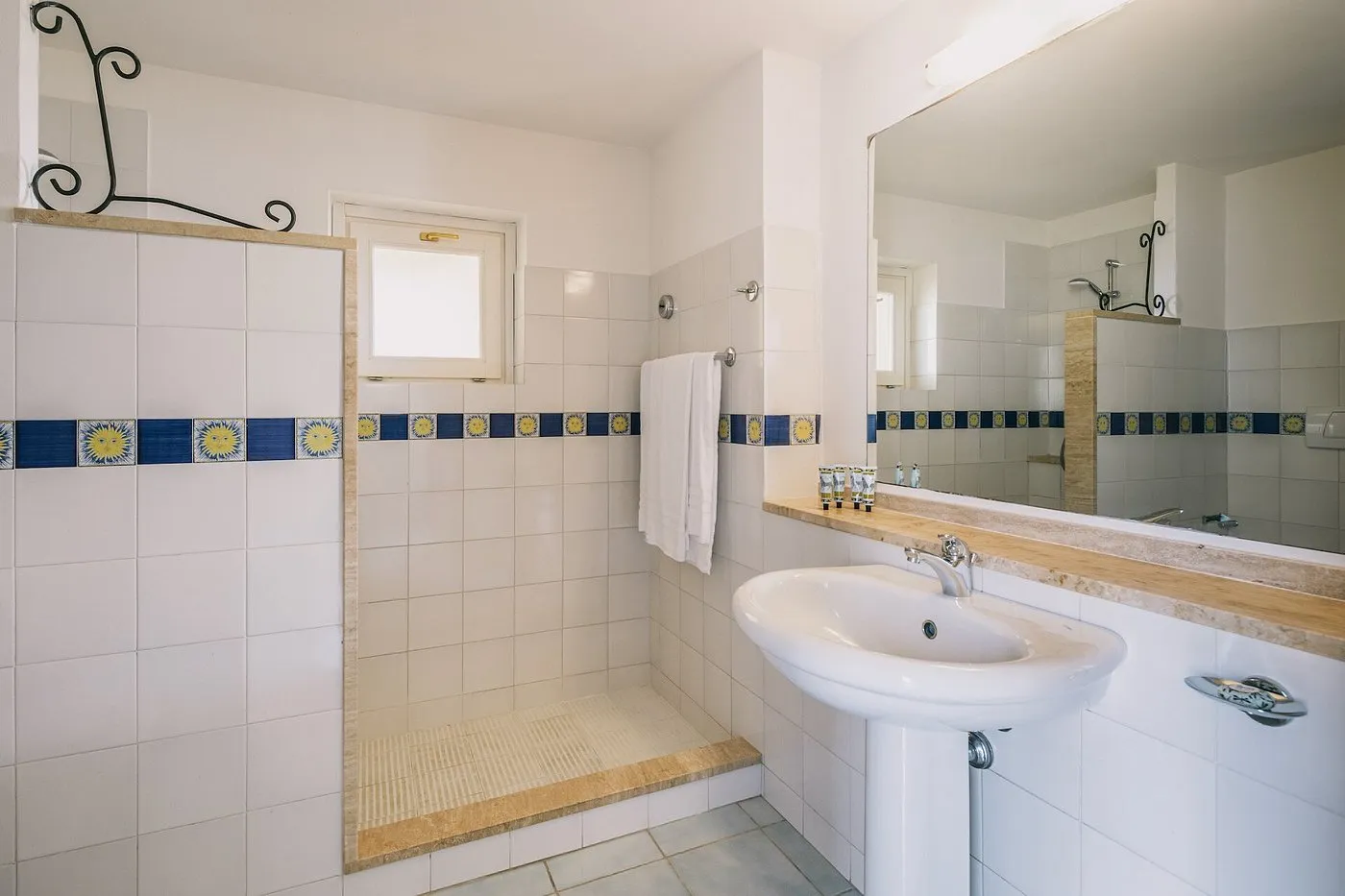 Bagno con doccia, lavabo e decorazioni in piastrelle blu e gialle
