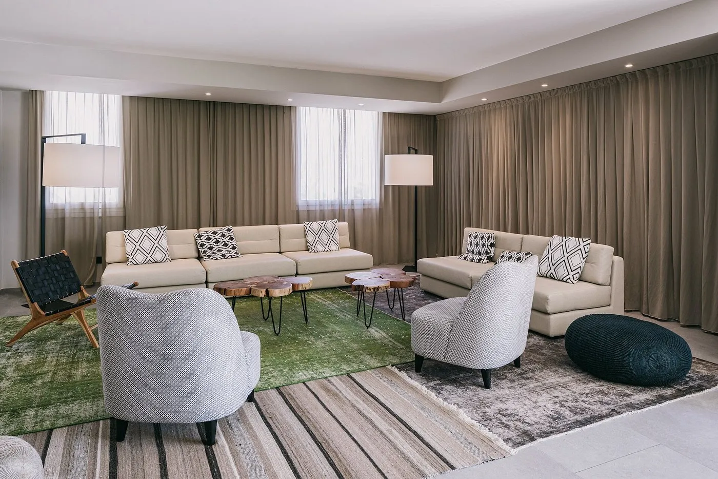 Salotto interno con divani beige, poltrone e tappeti dai toni neutri