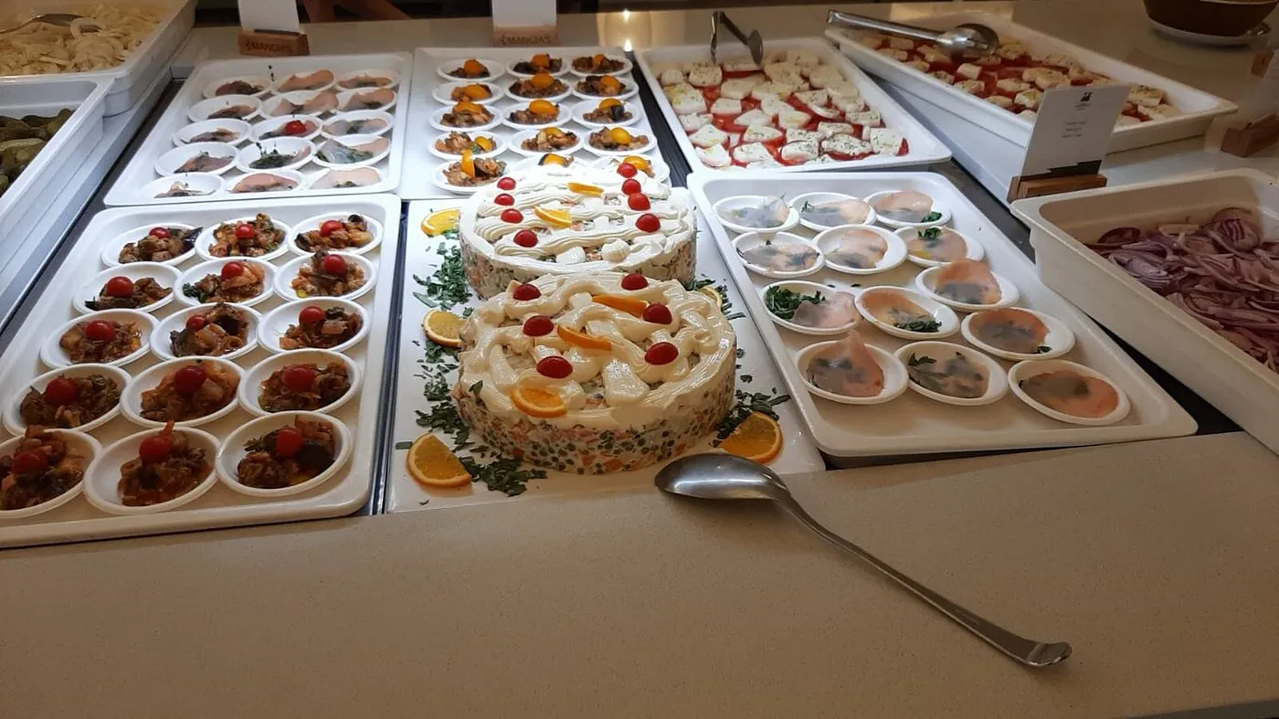 Buffet con antipasti, insalate e piatti decorati su vassoi bianchi