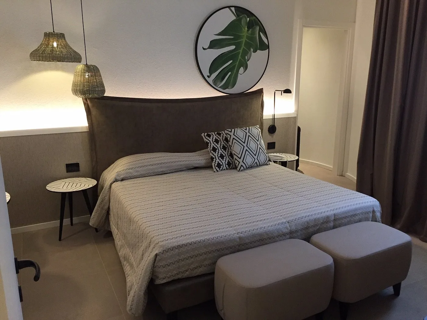 Camera con letto matrimoniale, pouf e quadro circolare con foglia tropicale