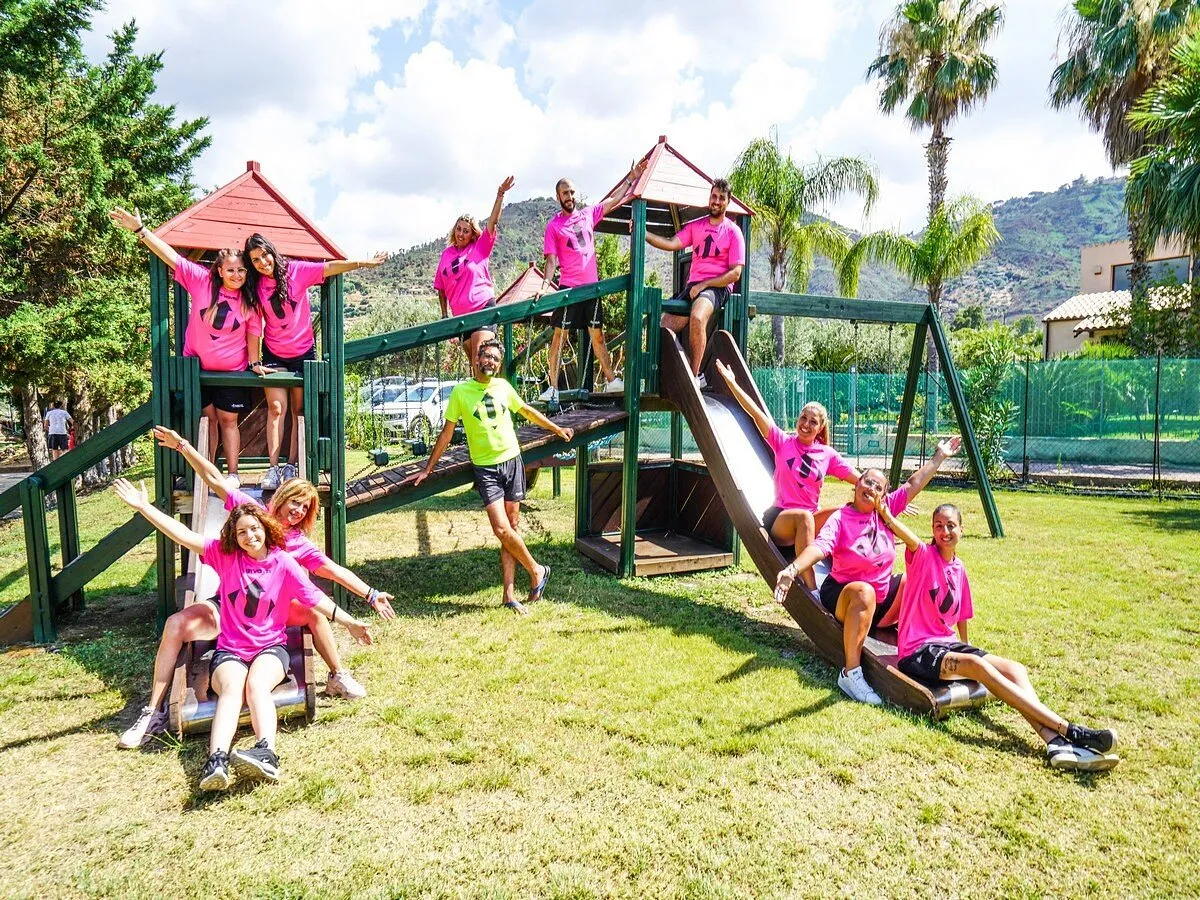 Team di animazione in maglietta rosa sullo scivolo del parco giochi