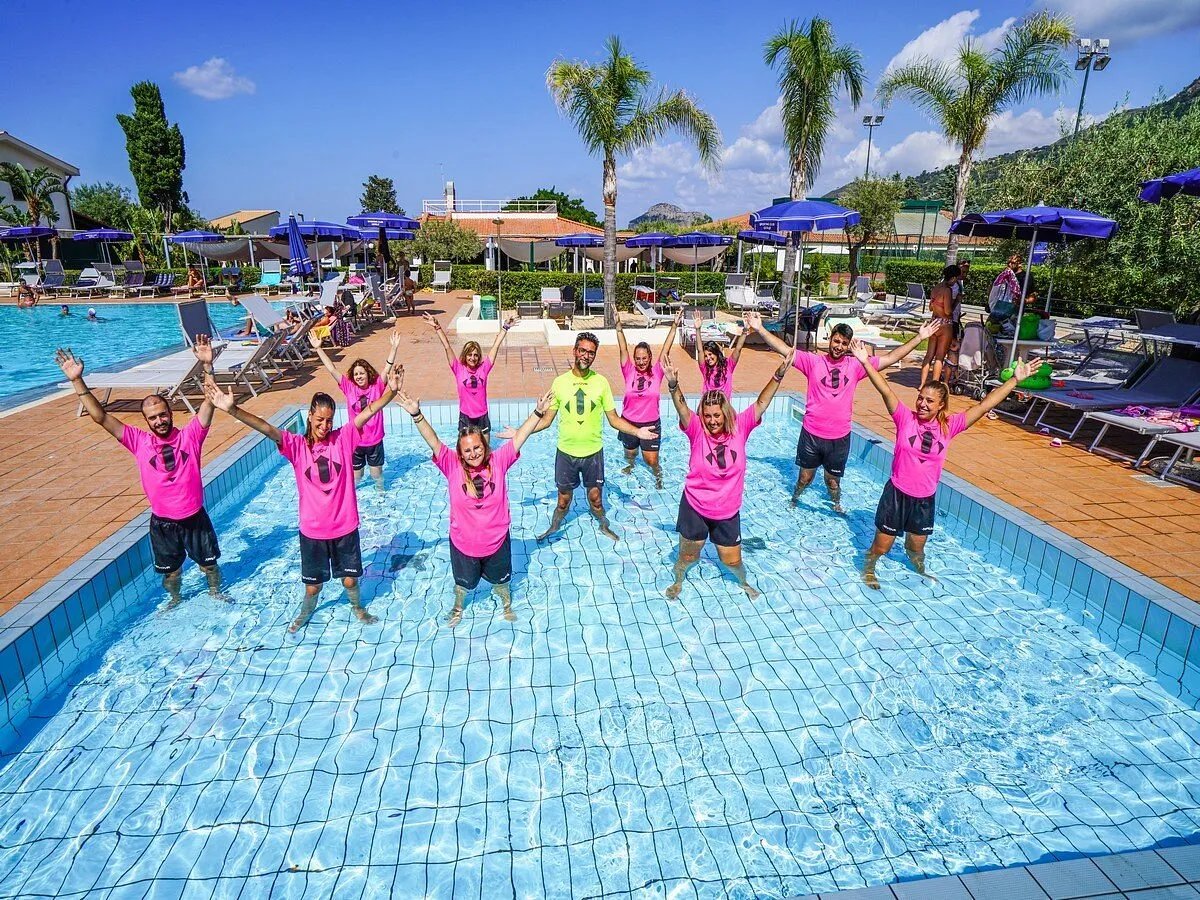 Animatori in piscina con braccia alzate durante attività