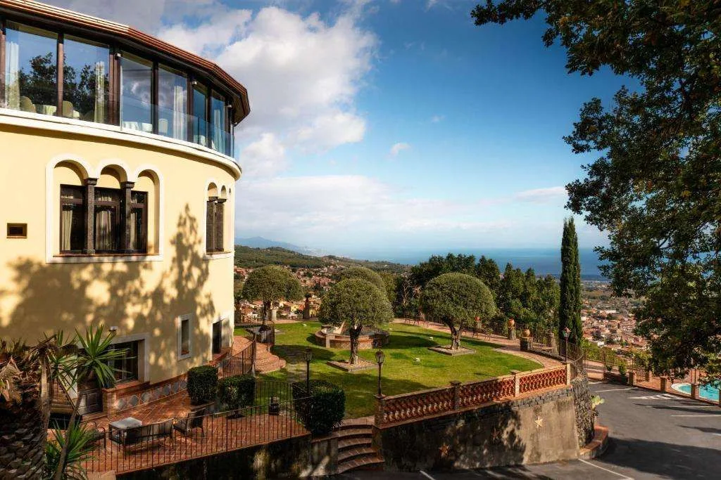 Esterno dell'hotel con giardino curato e vista sul mare e sulla costa