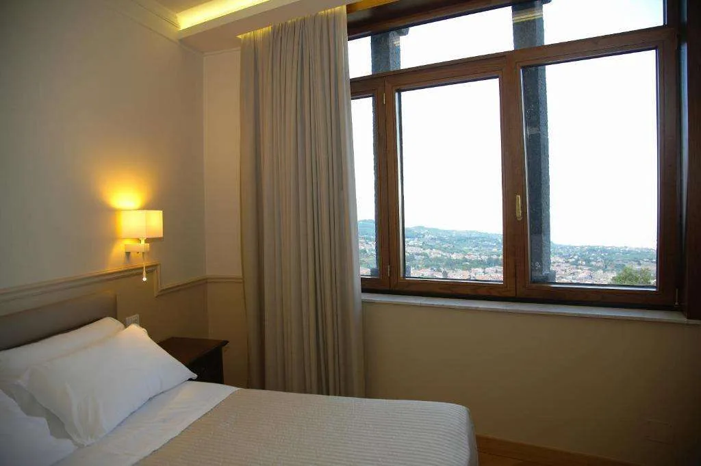 Camera con letto e finestra panoramica affacciata sulla città e le colline