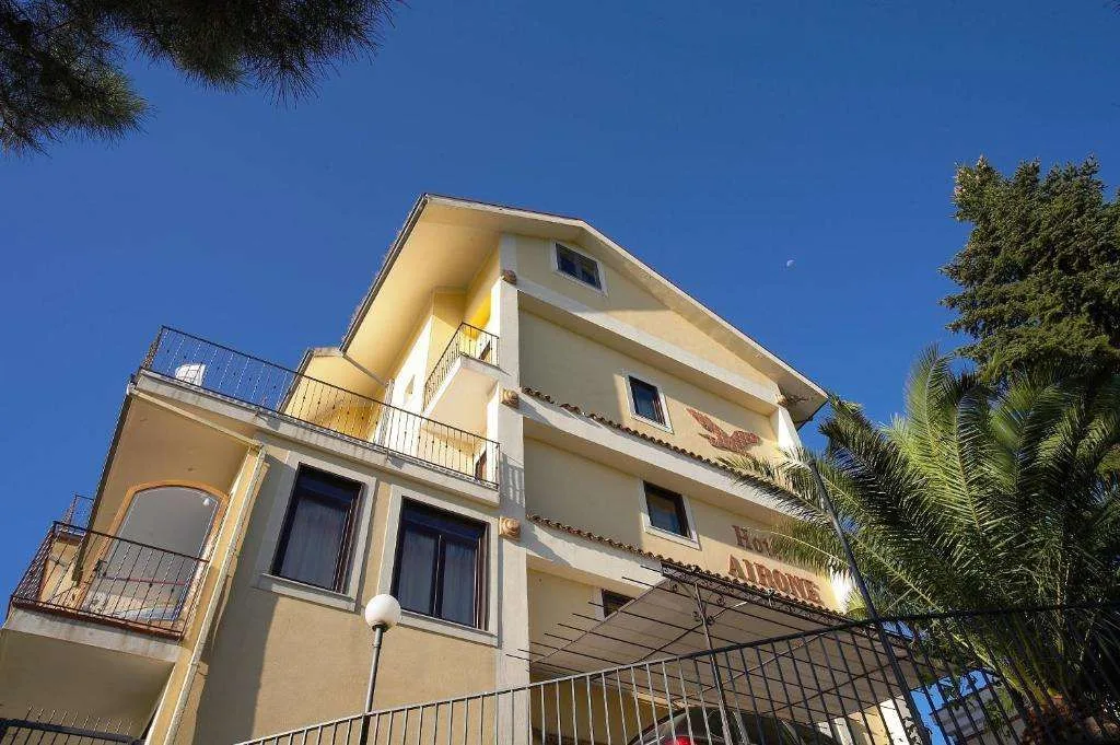 Facciata gialla dell'Hotel Airone con balconi e palma