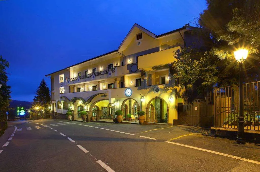 Esterno dell'hotel illuminato di sera con portici ad archi e orologio