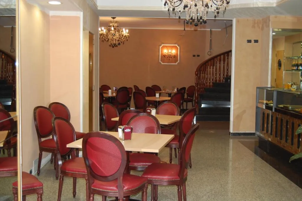 Sala colazioni con tavoli, sedie rosse, lampadari di cristallo e buffet