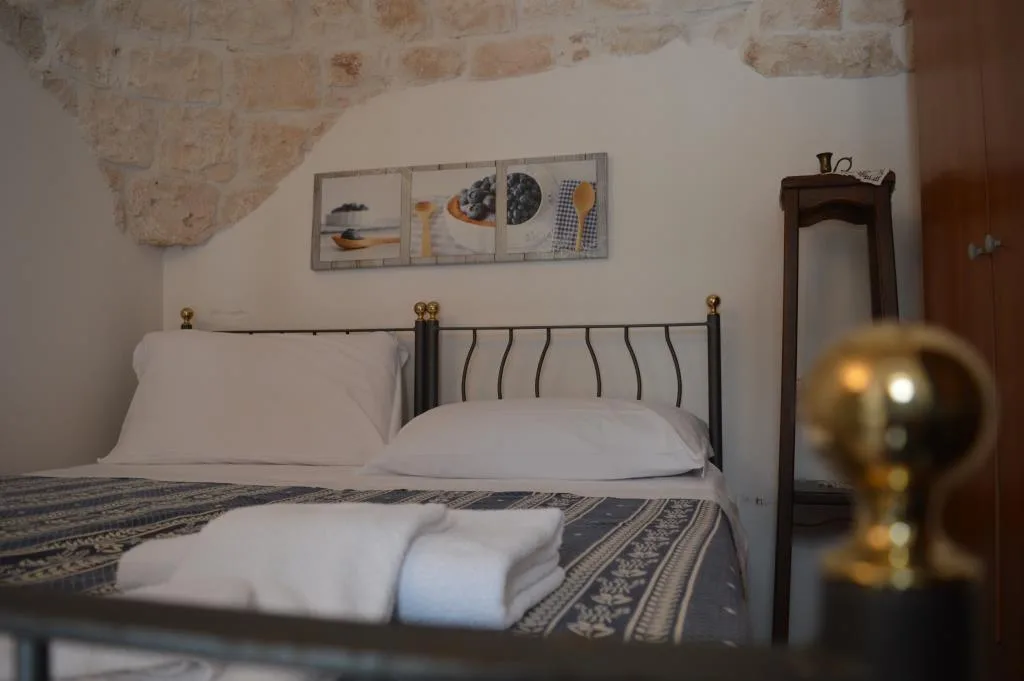 Camera con letto matrimoniale in ferro battuto e parete in pietra a vista