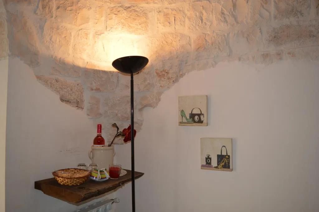 Angolo relax in trullo con lampada, mensola con vassoio e quadri alle pareti